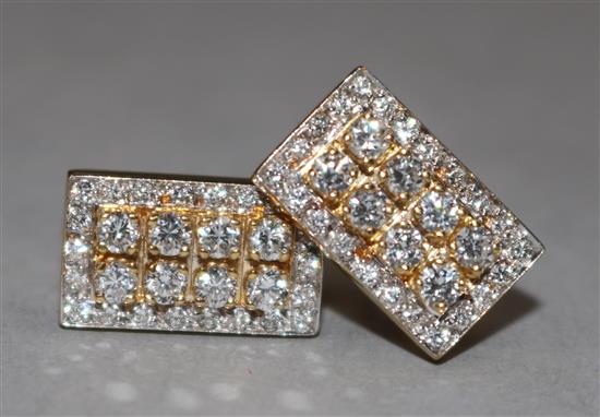 A pair of diamond earrings in rectangular yellow metal setting.